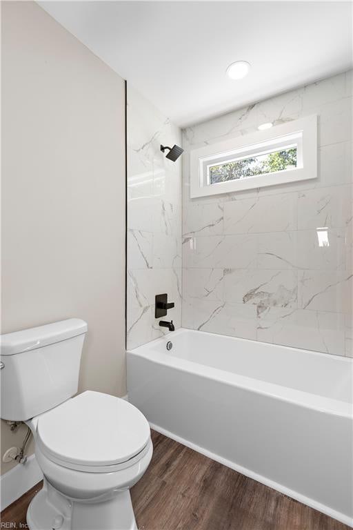 bathroom with tiled shower / bath combo, toilet, and wood-type flooring