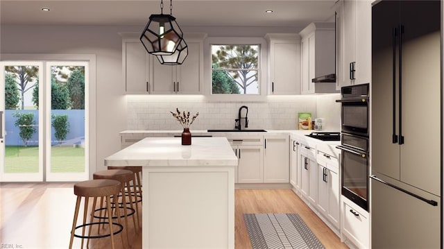 kitchen featuring high end refrigerator, decorative light fixtures, black oven, and a kitchen island