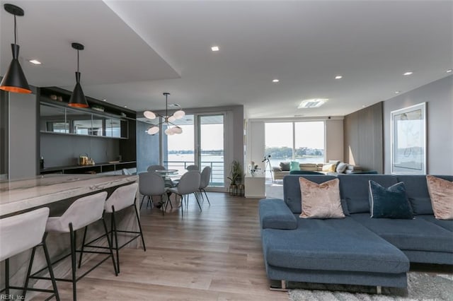 living room with a water view, a notable chandelier, and hardwood / wood-style flooring