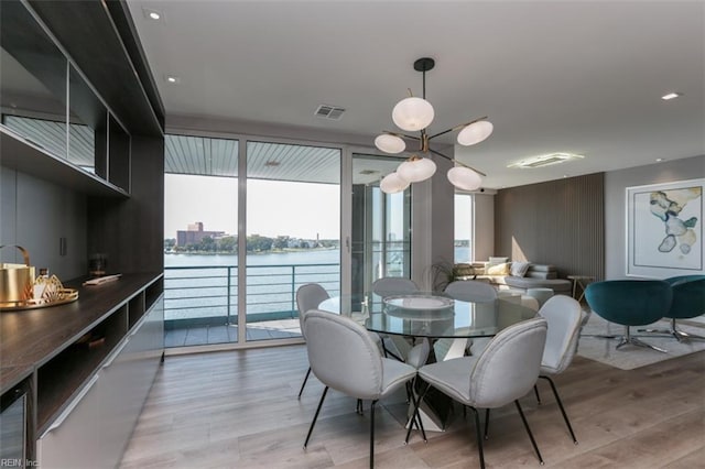 dining area with a water view, plenty of natural light, and light wood-type flooring