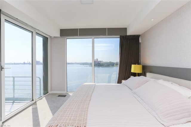 bedroom with a water view, light colored carpet, and access to outside