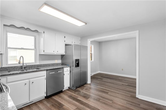 kitchen with dark stone countertops, dark wood-type flooring, sink, white cabinetry, and appliances with stainless steel finishes