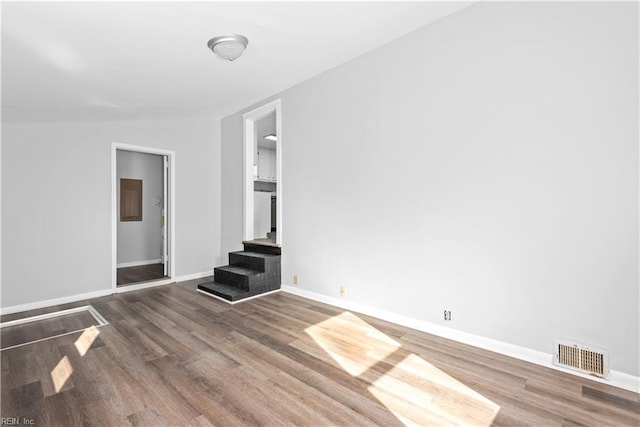 unfurnished living room featuring vaulted ceiling and dark hardwood / wood-style flooring