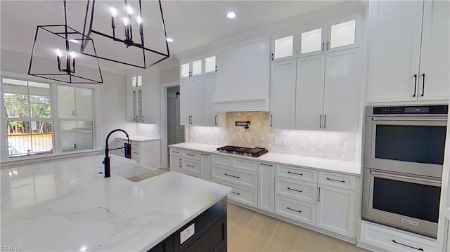 kitchen with appliances with stainless steel finishes, decorative light fixtures, white cabinets, decorative backsplash, and custom exhaust hood