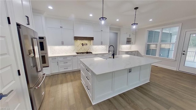 kitchen featuring white cabinetry, stainless steel appliances, sink, and a center island with sink