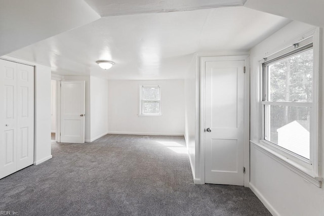 additional living space featuring vaulted ceiling and dark carpet