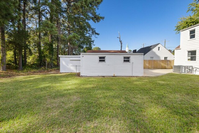 back of property featuring central air condition unit and a lawn