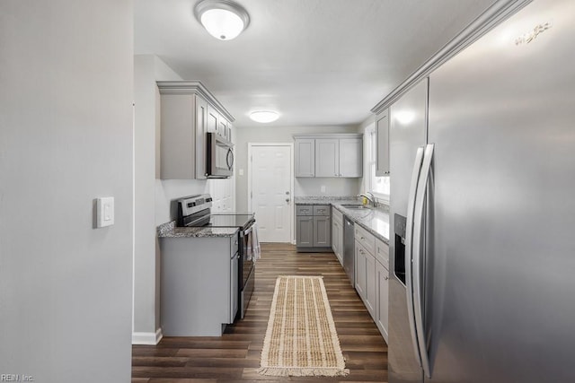 kitchen with sink, stone counters, gray cabinets, stainless steel appliances, and dark hardwood / wood-style flooring