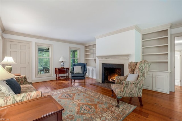 living room with hardwood / wood-style floors, crown molding, and built in features