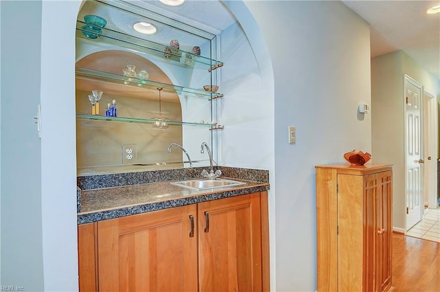 bar featuring light hardwood / wood-style floors and sink