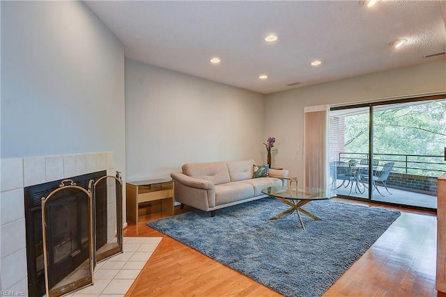 living room with a tile fireplace and light hardwood / wood-style flooring