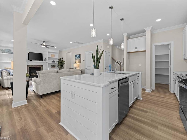 kitchen with appliances with stainless steel finishes, a center island with sink, sink, and white cabinetry