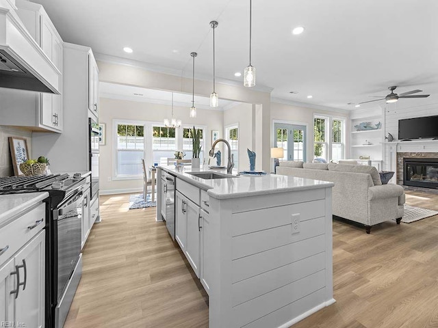 kitchen with custom exhaust hood, sink, a kitchen island with sink, white cabinetry, and appliances with stainless steel finishes