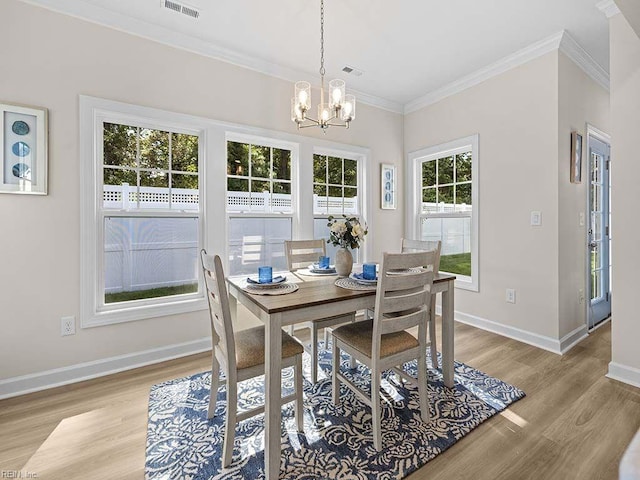 dining area featuring crown molding, a chandelier, light wood-type flooring, and a healthy amount of sunlight