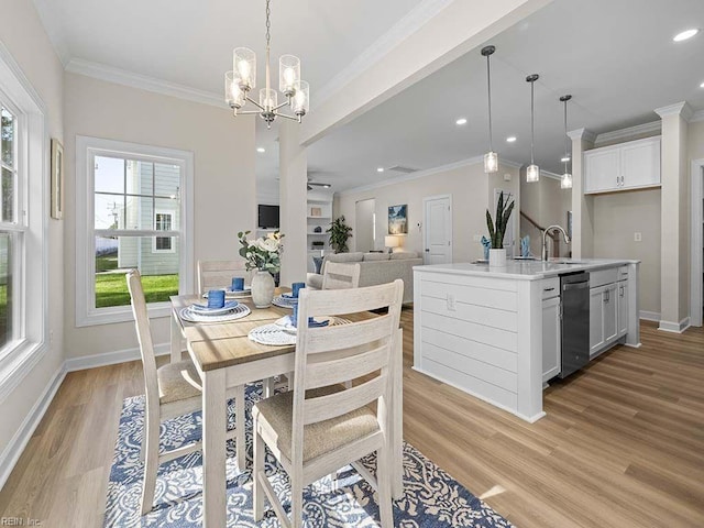 dining space with crown molding, a notable chandelier, light wood-type flooring, and sink