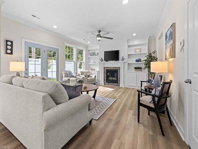 living room featuring ceiling fan, hardwood / wood-style flooring, crown molding, and built in features