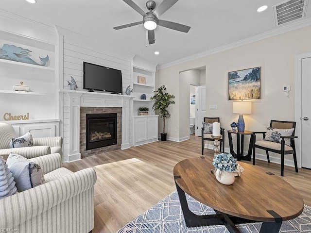 living room featuring crown molding, ceiling fan, built in shelves, and light hardwood / wood-style floors