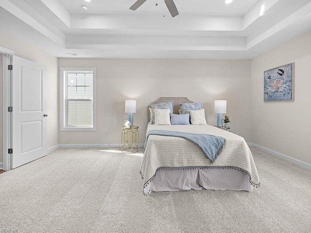 carpeted bedroom featuring a raised ceiling and ceiling fan