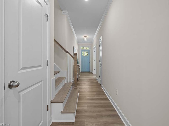 hallway with ornamental molding and light hardwood / wood-style flooring