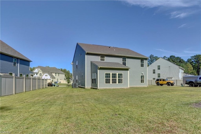 back of house with central AC unit and a yard