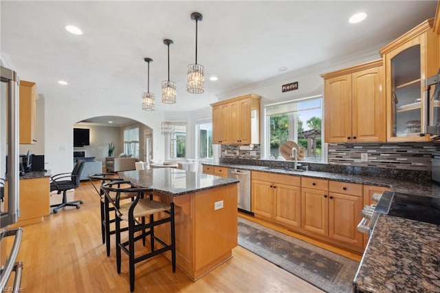 kitchen with sink, stainless steel dishwasher, decorative light fixtures, light hardwood / wood-style flooring, and a center island