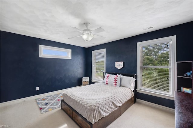 bedroom with light colored carpet, multiple windows, and ceiling fan