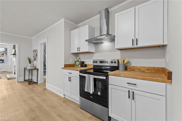 kitchen with wall chimney range hood, stainless steel range with electric cooktop, light hardwood / wood-style flooring, white cabinets, and butcher block countertops