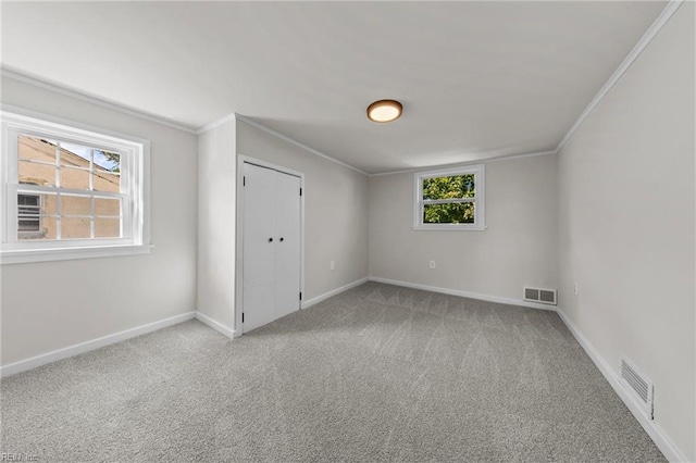 spare room featuring ornamental molding, a wealth of natural light, and light carpet