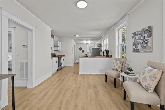 kitchen featuring stainless steel appliances, light wood-type flooring, butcher block counters, and white cabinetry