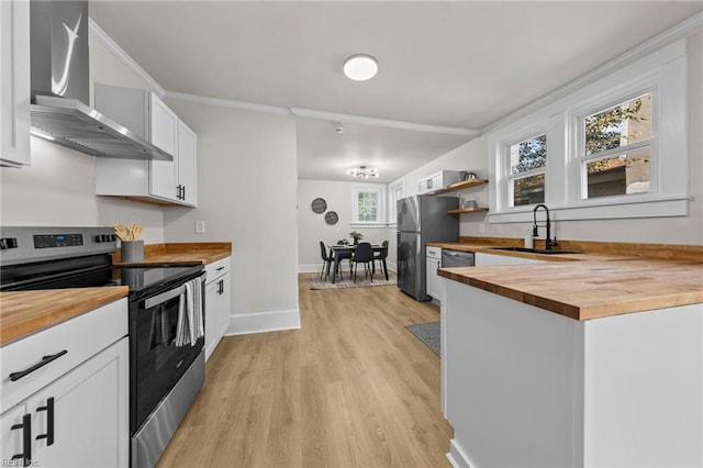 kitchen with sink, butcher block countertops, wall chimney range hood, stainless steel appliances, and a wealth of natural light