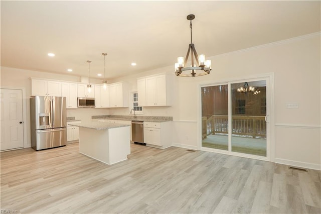 kitchen with white cabinets, decorative light fixtures, light hardwood / wood-style floors, and appliances with stainless steel finishes