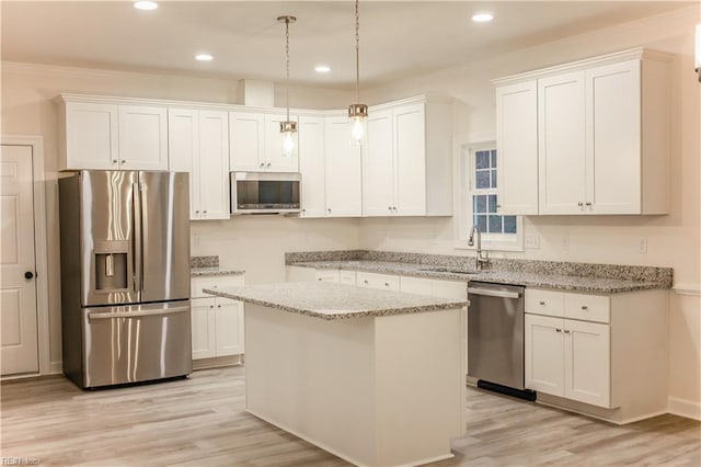 kitchen featuring white cabinets, stainless steel appliances, a kitchen island, and sink