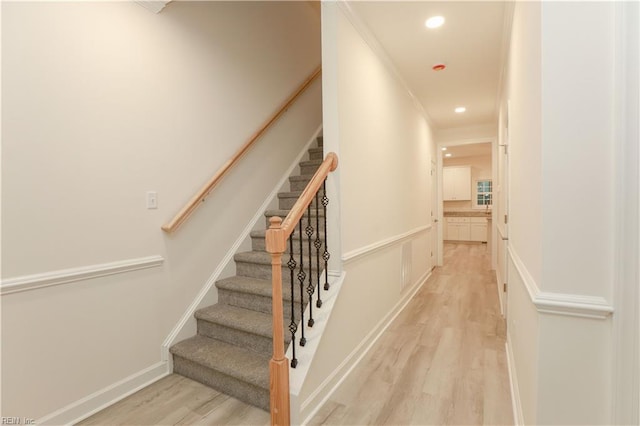 stairs featuring hardwood / wood-style floors and crown molding