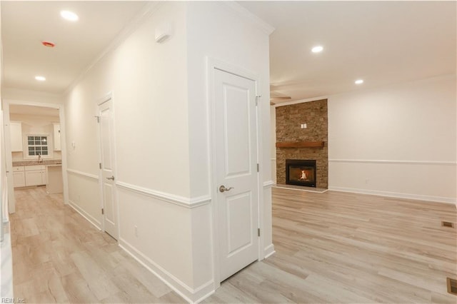 hallway with light hardwood / wood-style floors and ornamental molding