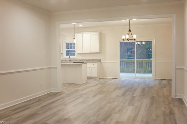 interior space featuring white cabinets, decorative light fixtures, light hardwood / wood-style floors, and a notable chandelier