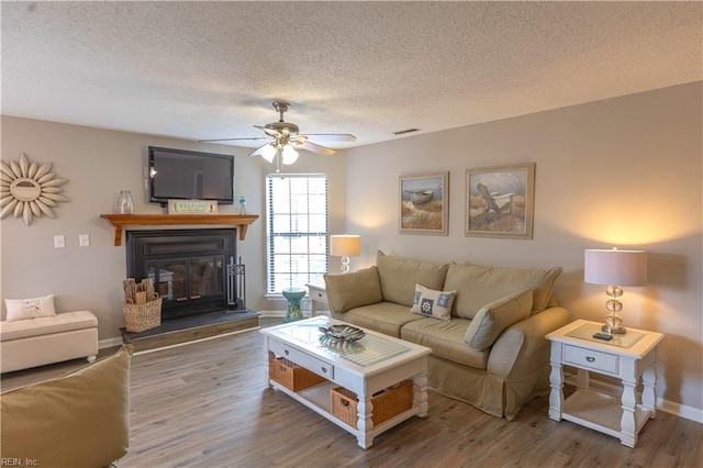 living room with wood-type flooring, ceiling fan, and a textured ceiling