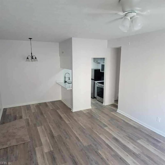 unfurnished living room with hardwood / wood-style flooring and ceiling fan with notable chandelier