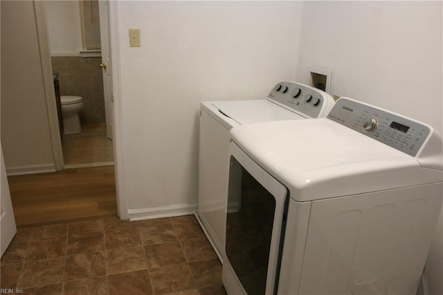 laundry area featuring tile walls, dark hardwood / wood-style floors, and washing machine and clothes dryer