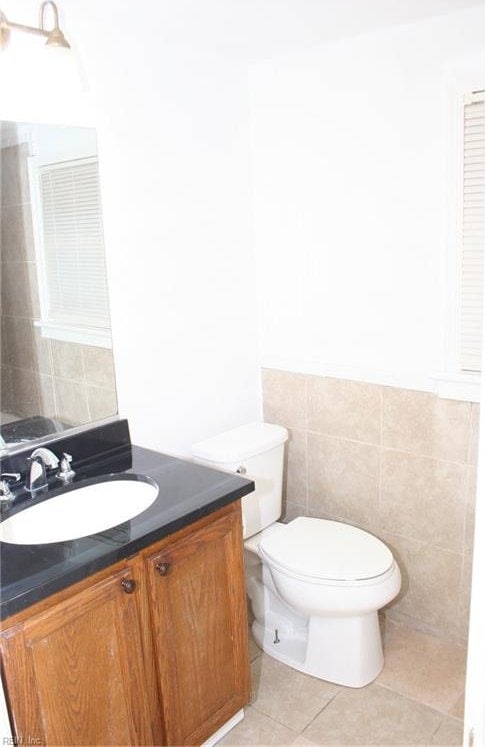 bathroom with toilet, tile patterned flooring, vanity, and tile walls