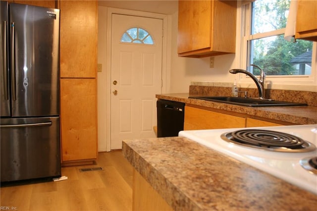 kitchen with white stove, stainless steel refrigerator, sink, black dishwasher, and light hardwood / wood-style flooring