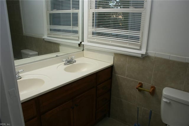 bathroom with vanity, tile walls, and toilet