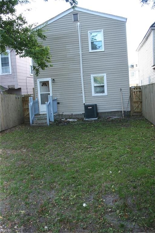 back of property featuring central AC unit and a yard