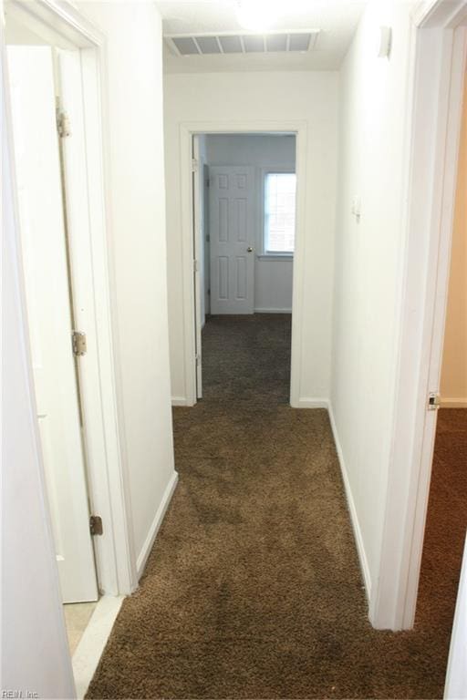 hall featuring dark carpet