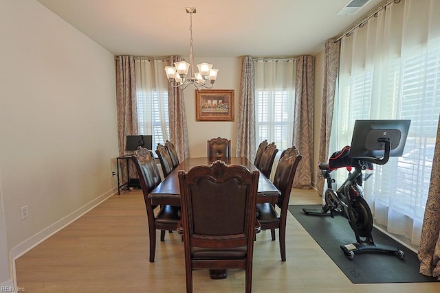 dining space featuring plenty of natural light, light hardwood / wood-style floors, and an inviting chandelier