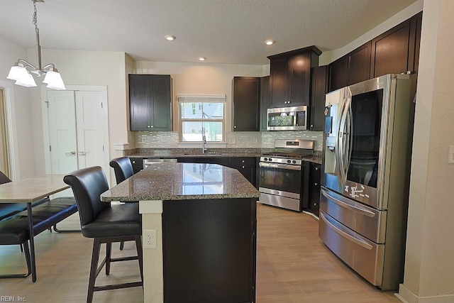 kitchen featuring pendant lighting, a kitchen island, stainless steel appliances, a breakfast bar, and light hardwood / wood-style floors