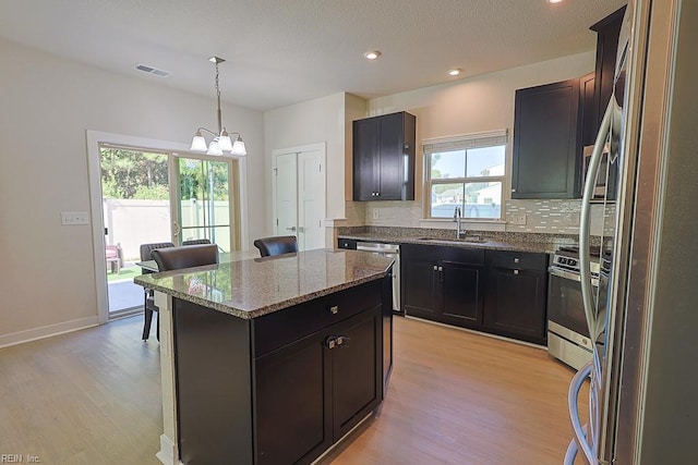 kitchen with a center island, stainless steel appliances, sink, light hardwood / wood-style flooring, and decorative light fixtures