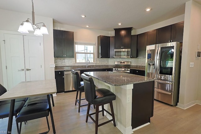 kitchen featuring a kitchen island, light hardwood / wood-style flooring, sink, hanging light fixtures, and appliances with stainless steel finishes