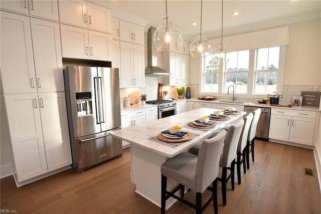 kitchen featuring a kitchen island, high end appliances, sink, dark hardwood / wood-style flooring, and wall chimney range hood