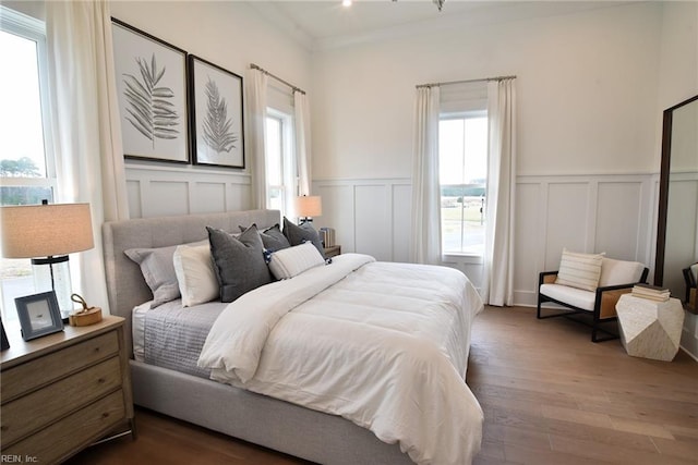 bedroom featuring ornamental molding, hardwood / wood-style floors, and multiple windows