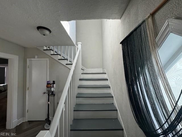 stairs featuring wood-type flooring and a textured ceiling